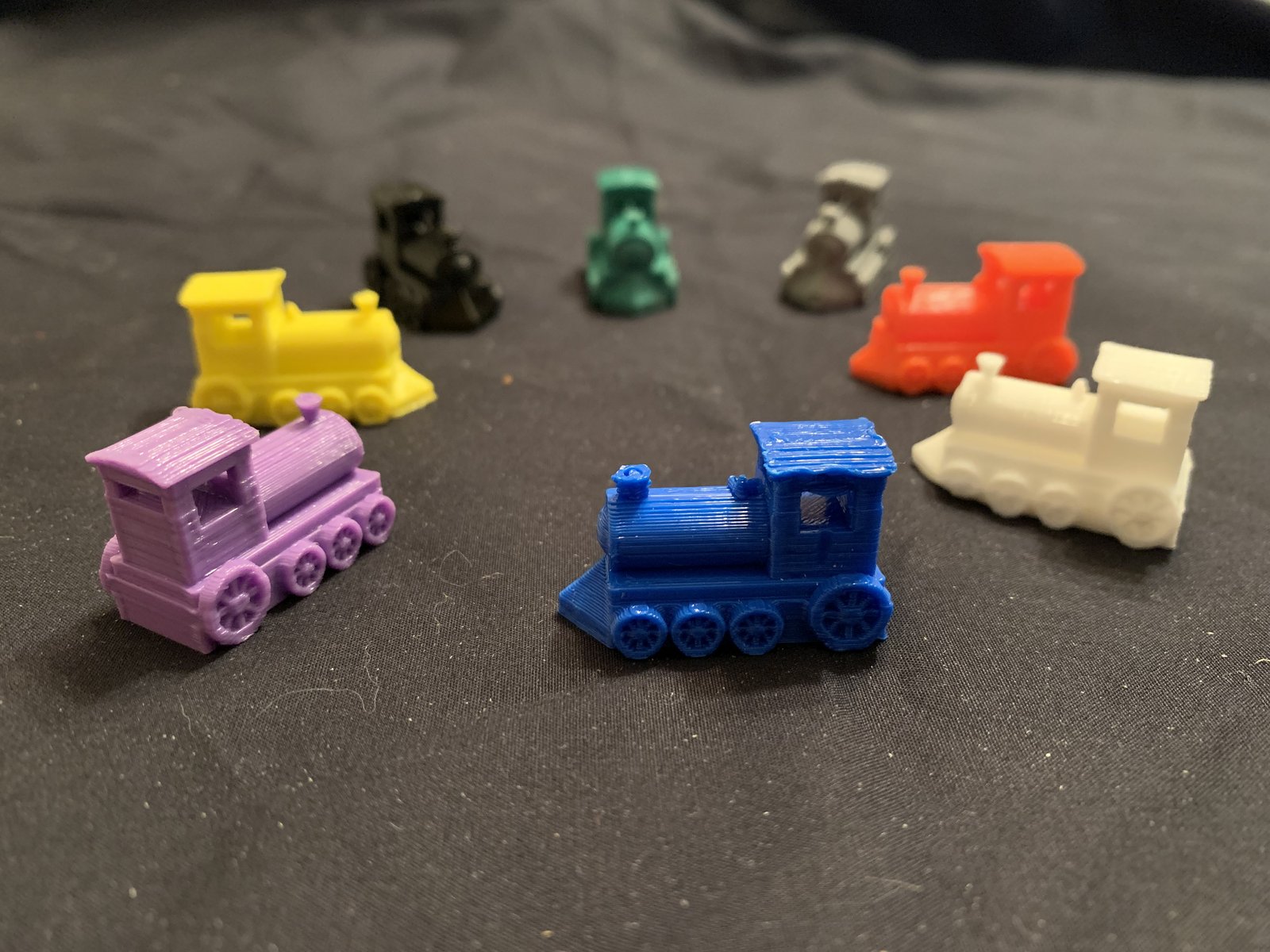 Set of small 3D printed train-shaped domino pieces in assorted colors