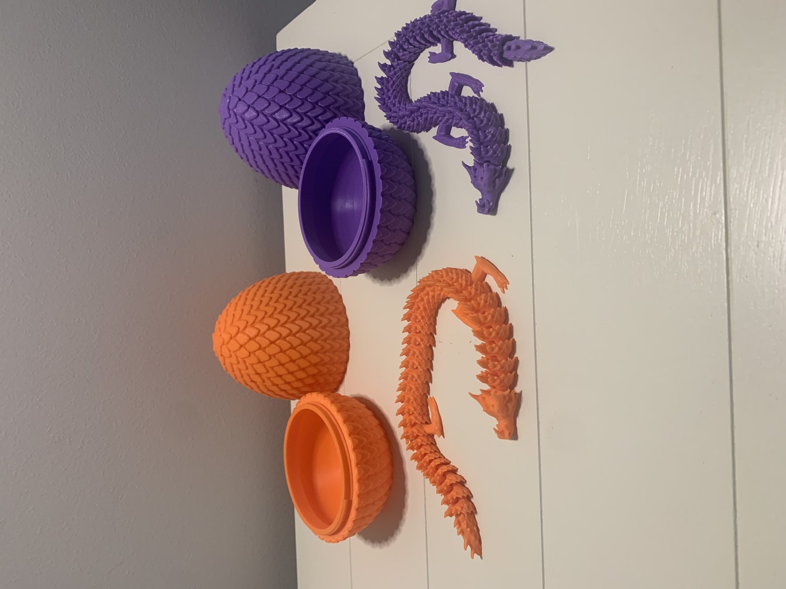 3D printed dragon eggs that screw apart to reveal a dragon inside, in orange and purple